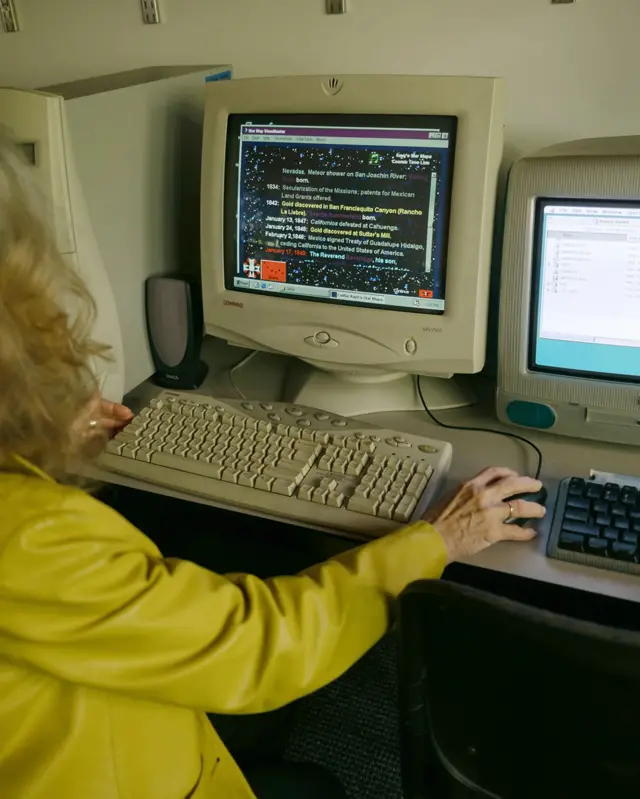Літня жінка за вінтажним ПК Microsoft з космічною програмою на екрані