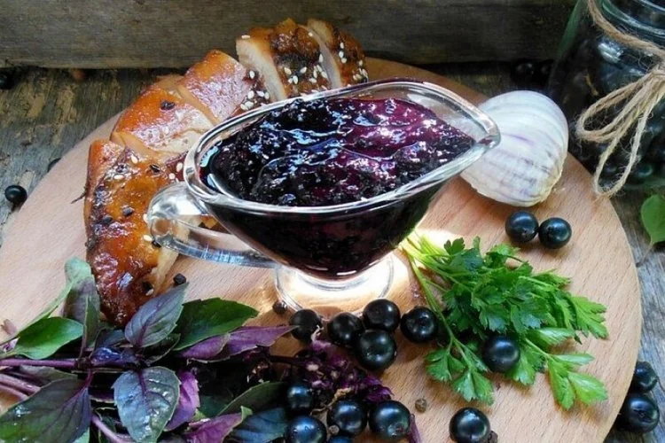Чорносмородиновий соус у соуснику з мясом та ягодами на дошці