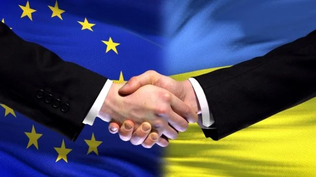 Рукостискання представників ЄС та України на тлі прапорів