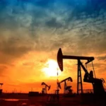 Нафтові качалки на тлі яскравого заходу сонця, що ілюструє зростання цін на Brent через напругу на Близькому Сході.