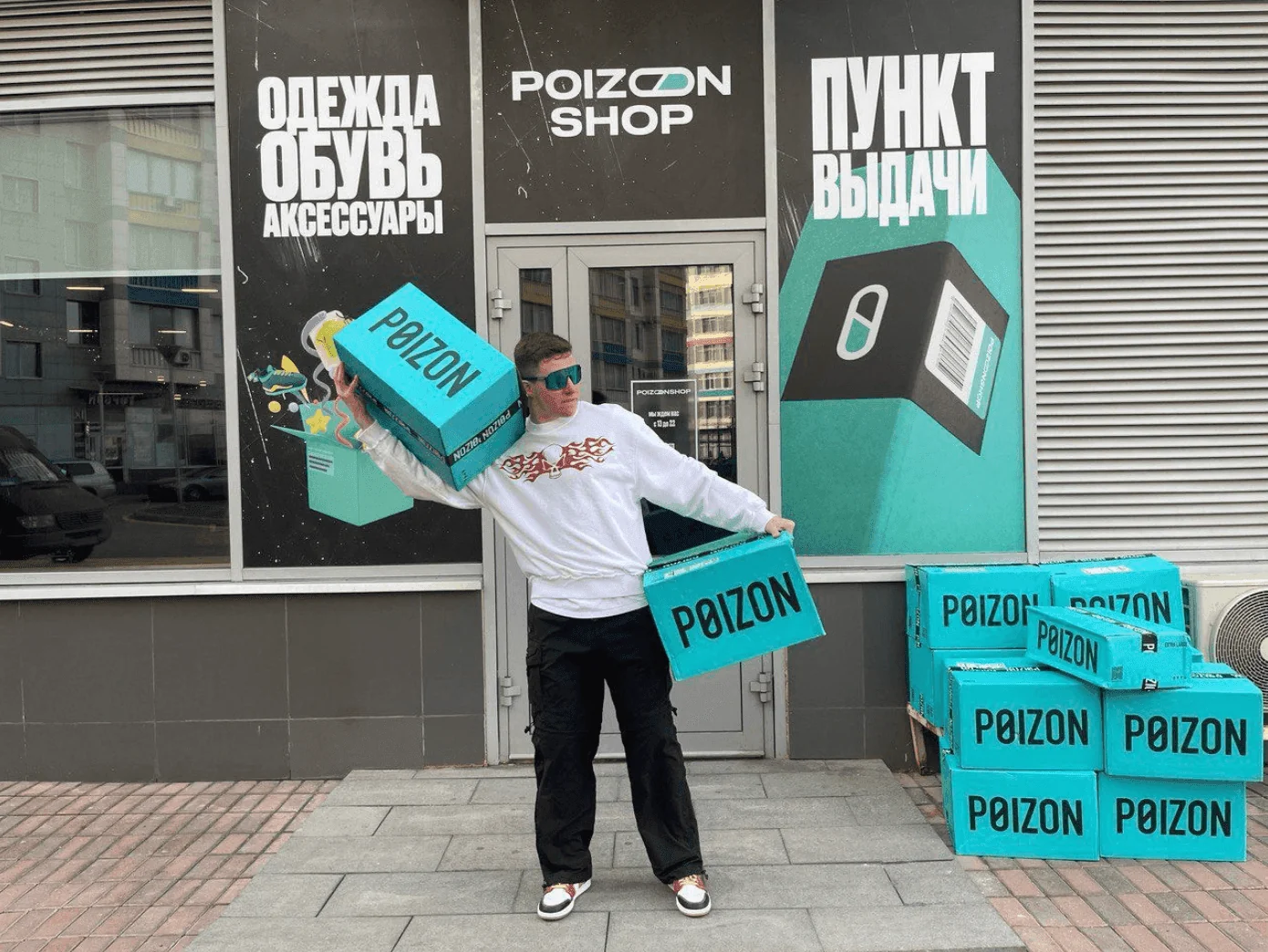 Чоловік з коробками Poizon перед фейковим магазином Poizon Shop у Росії