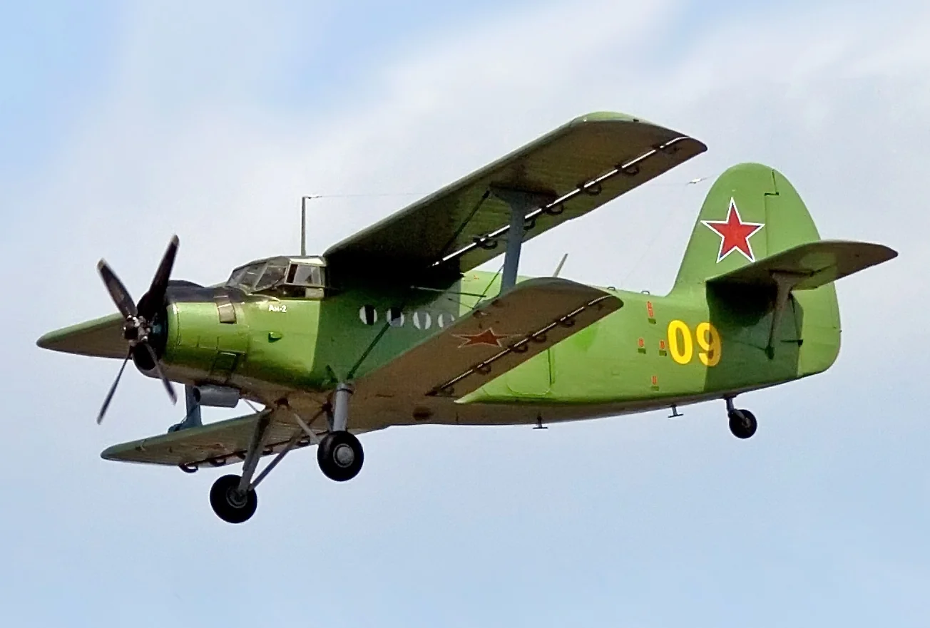 Зелений біплан Ан-2 з червоними зірками та номером 09 у польоті