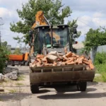Екскаватор навантажує цеглу з руїн під час відбудови Вишневого