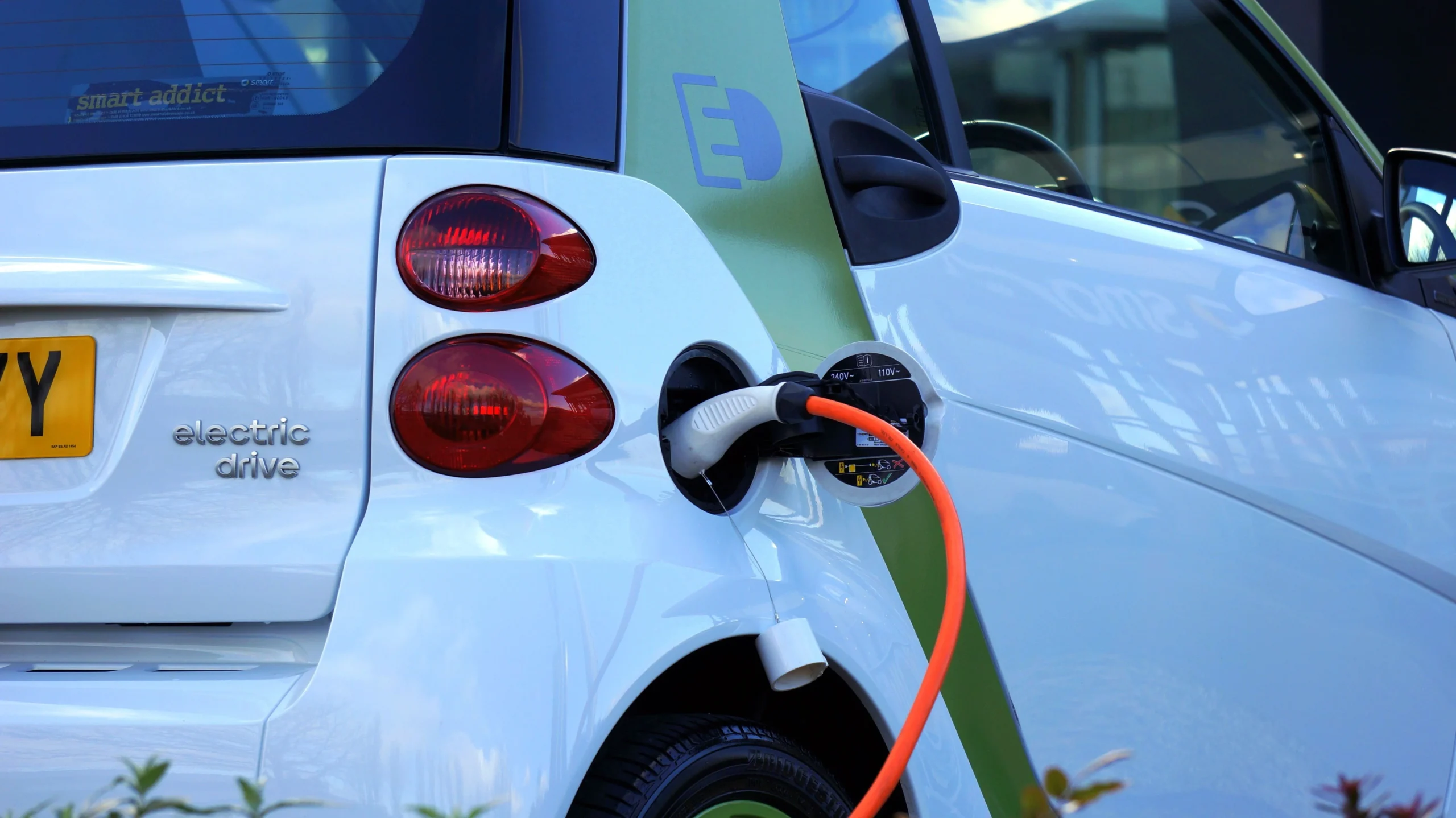Білий електромобіль Smart із підключеним помаранчевим зарядним кабелем